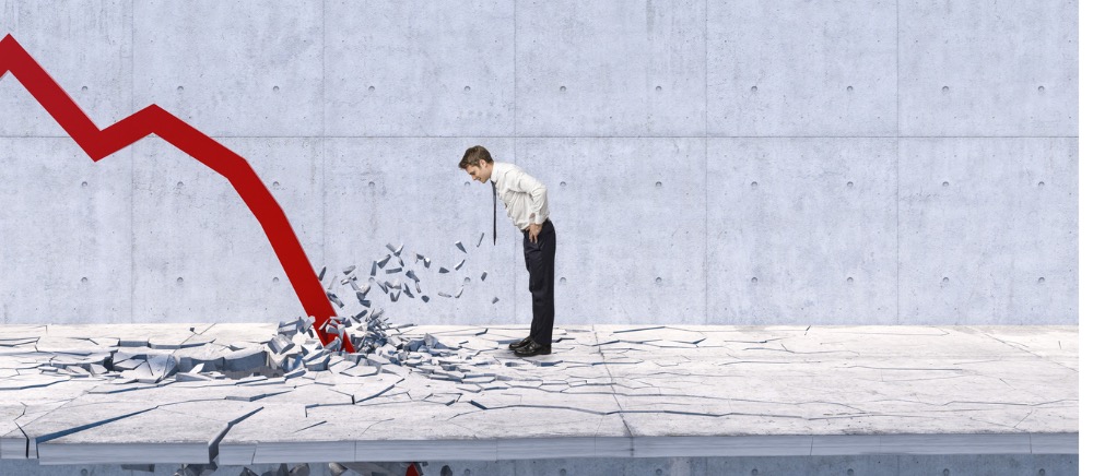 Man looking at cracked concrete as red graph line decreases