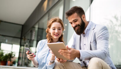 Two people smiling while looking at an ipad