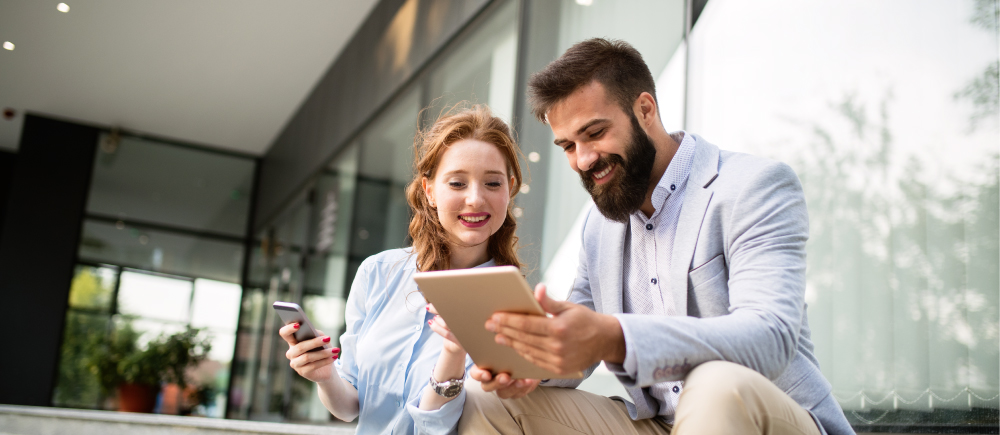 Two people smiling while looking at an ipad