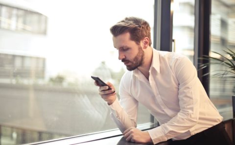 Man wearing a white button up look at his phone