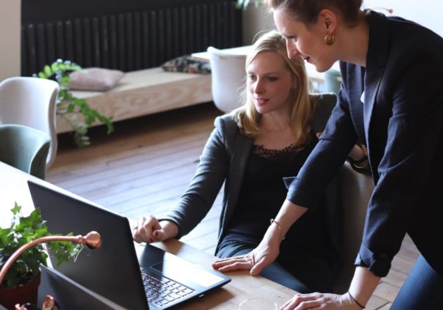 Two female professionals looking at a computer