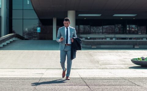 Man in a business suit walking while on his phone