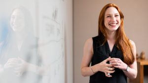 Woman standing by whiteboard smiling