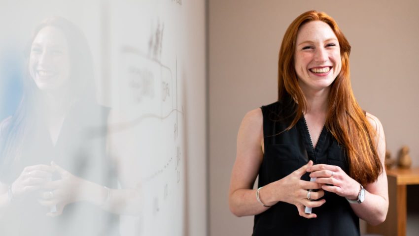 Woman standing by whiteboard smiling
