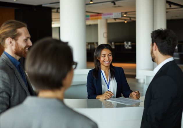 Three employees checking in with front desk security staff