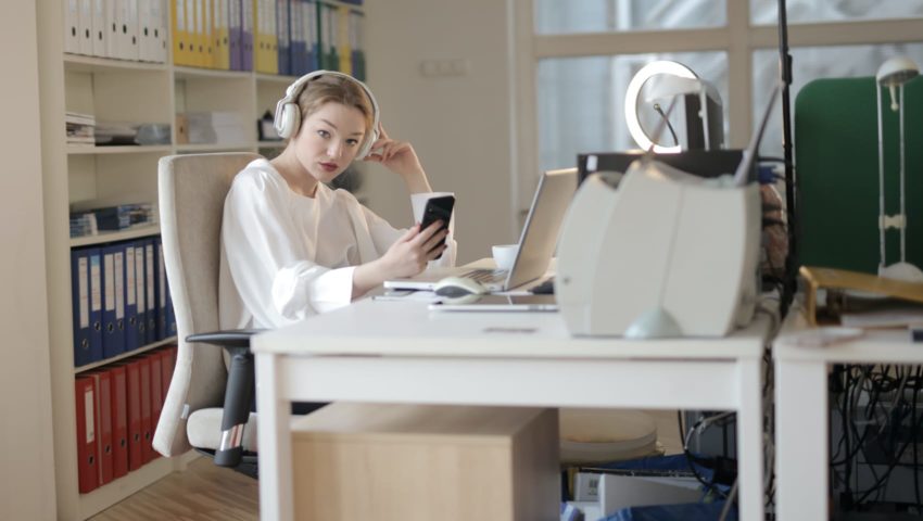 Unhappy female sitting by phone and computer