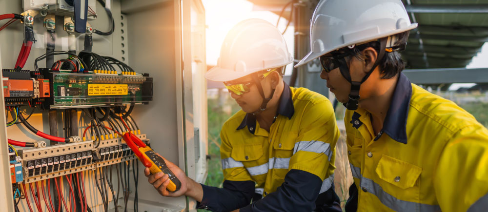 Two maintenance workers inspect wiring as part of their preventive maintenance plan