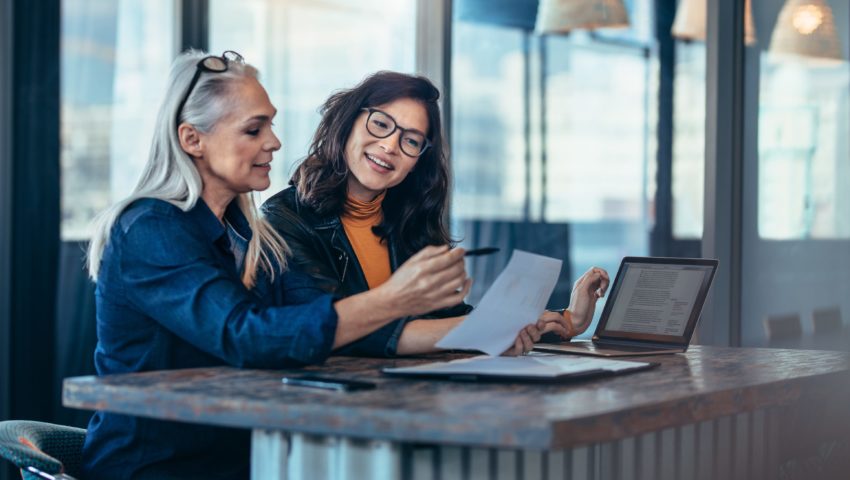 Two women looking at a computer screen and talking