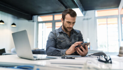 Man using a cellphone for property management budget planning.