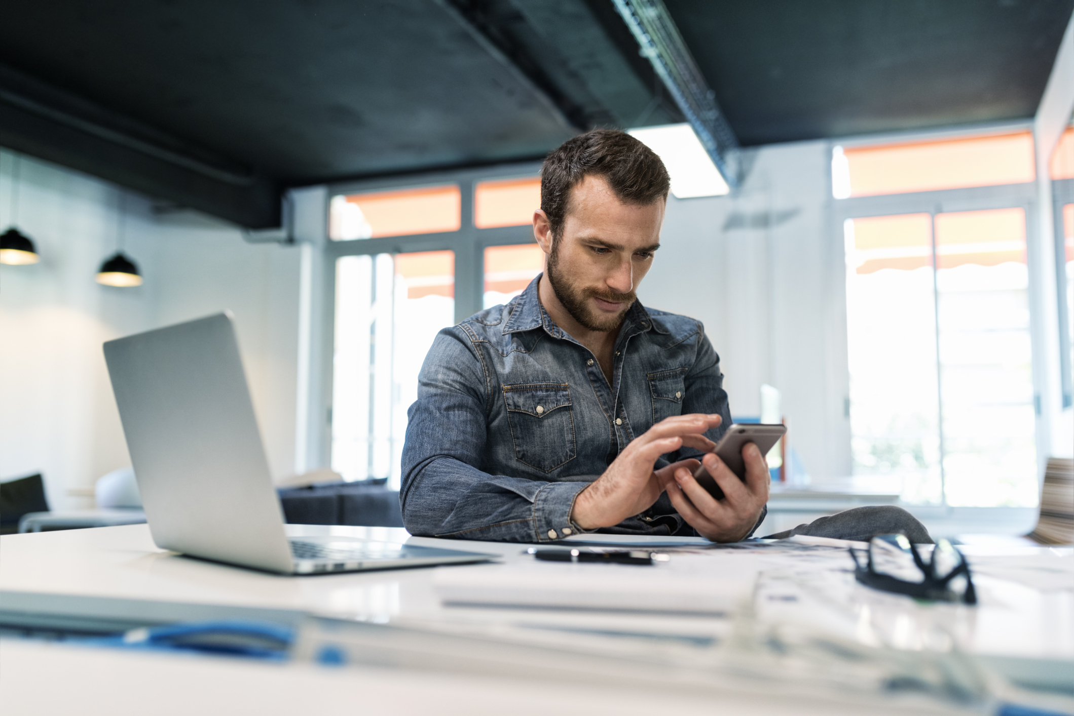 Man using a cellphone for property management budget planning.