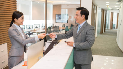 Receptionist welcoming building visitor aided by visitor management software.