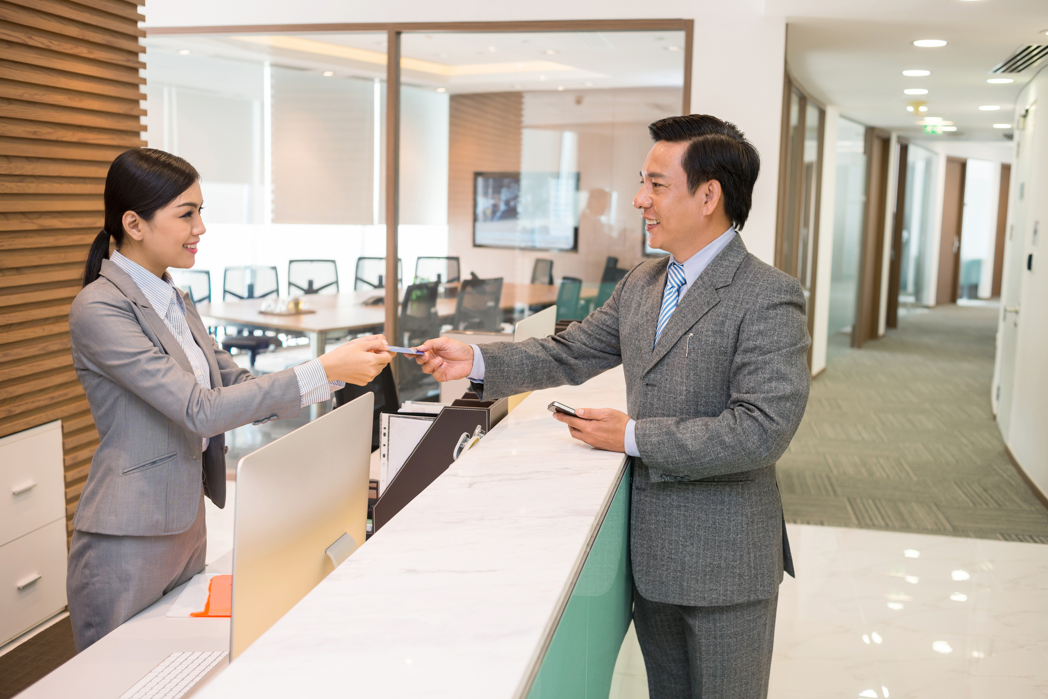 Receptionist welcoming building visitor aided by visitor management software.