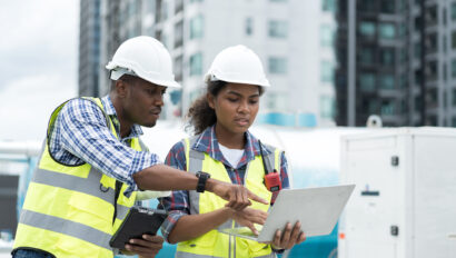 Group of African American engineer working in sewer pipes area at construction site. Male engineer and woman engineer discussing for maintenance sewer pipes, water tank on rooftop of building