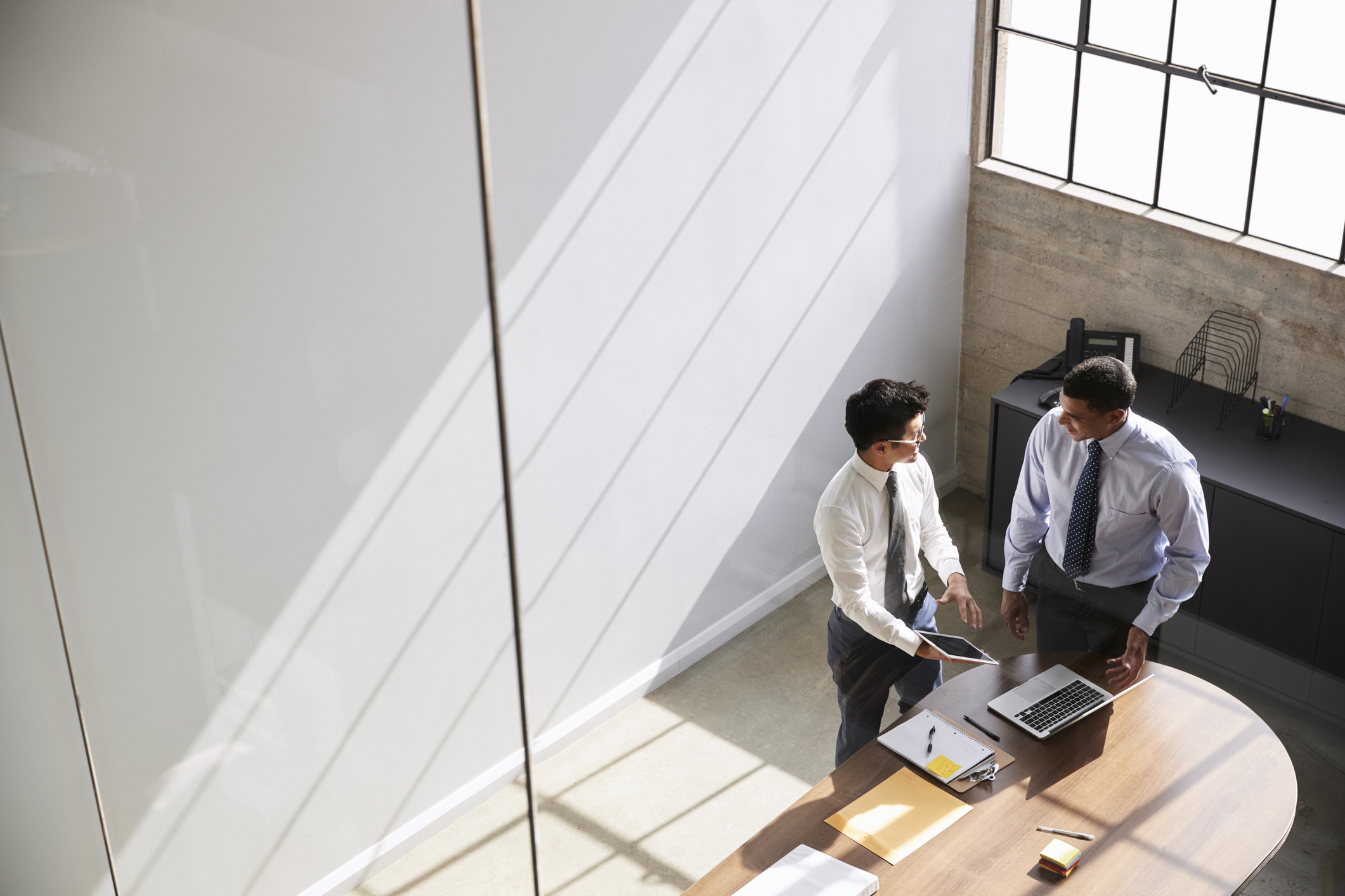 Two businessmen in discussion using laptop, elevated view