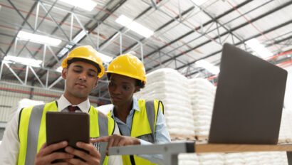 Male and female manager discussing over digital tablet at desk in warehouse