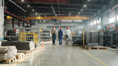 Rear view of three engineers leaving workshop at the end of working day