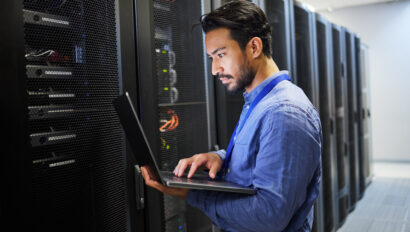 Programming, data center and a man with a laptop for maintenance, cyber security and internet check. Coding, email and an Asian programmer typing on a computer for network or server analytics